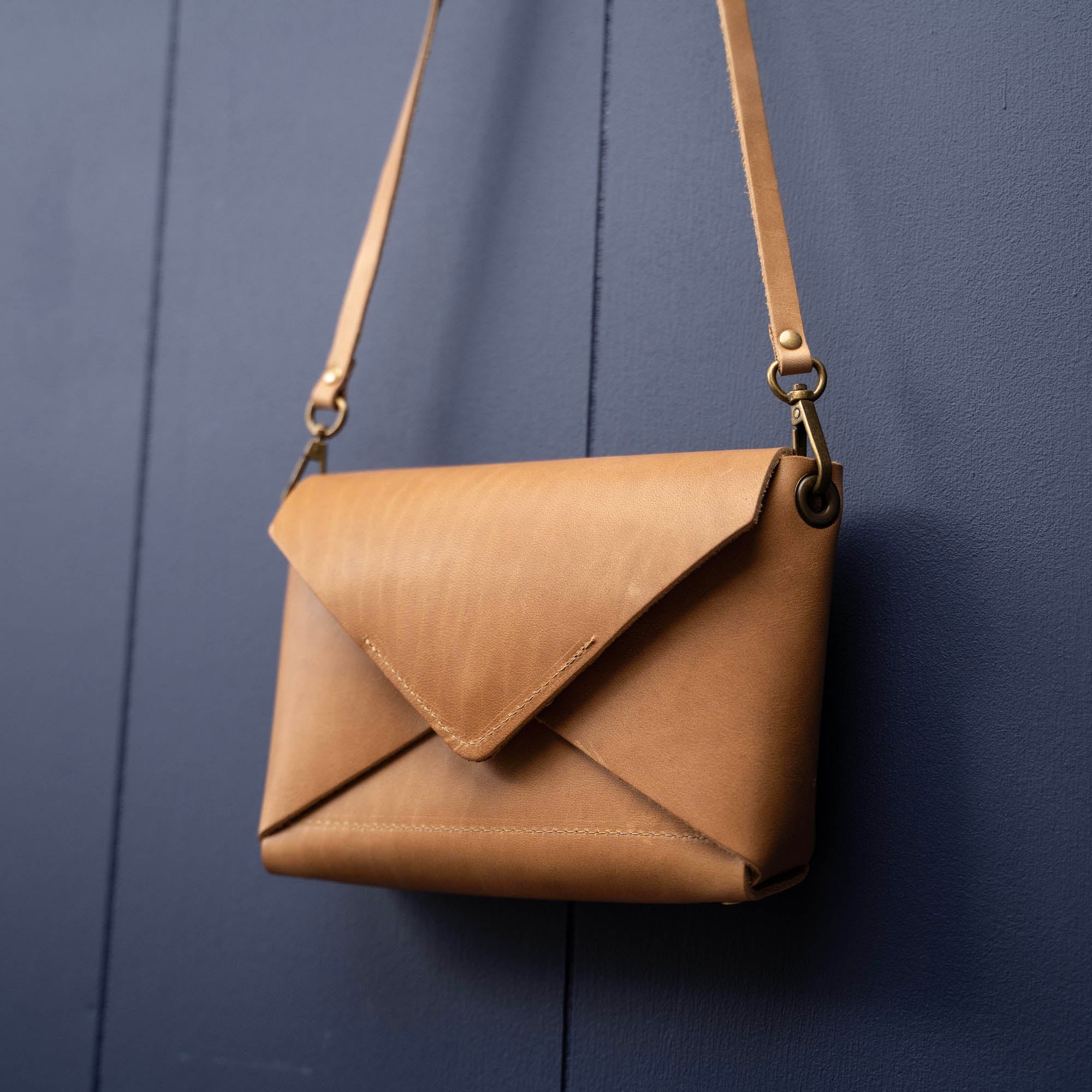 Handmade envelope purse featuring 3 in 1 leather strap. Wear as a clutch, wristlet, crossbody, or over the shoulder. Made with full grain leather. Available in black, brown, or tan.