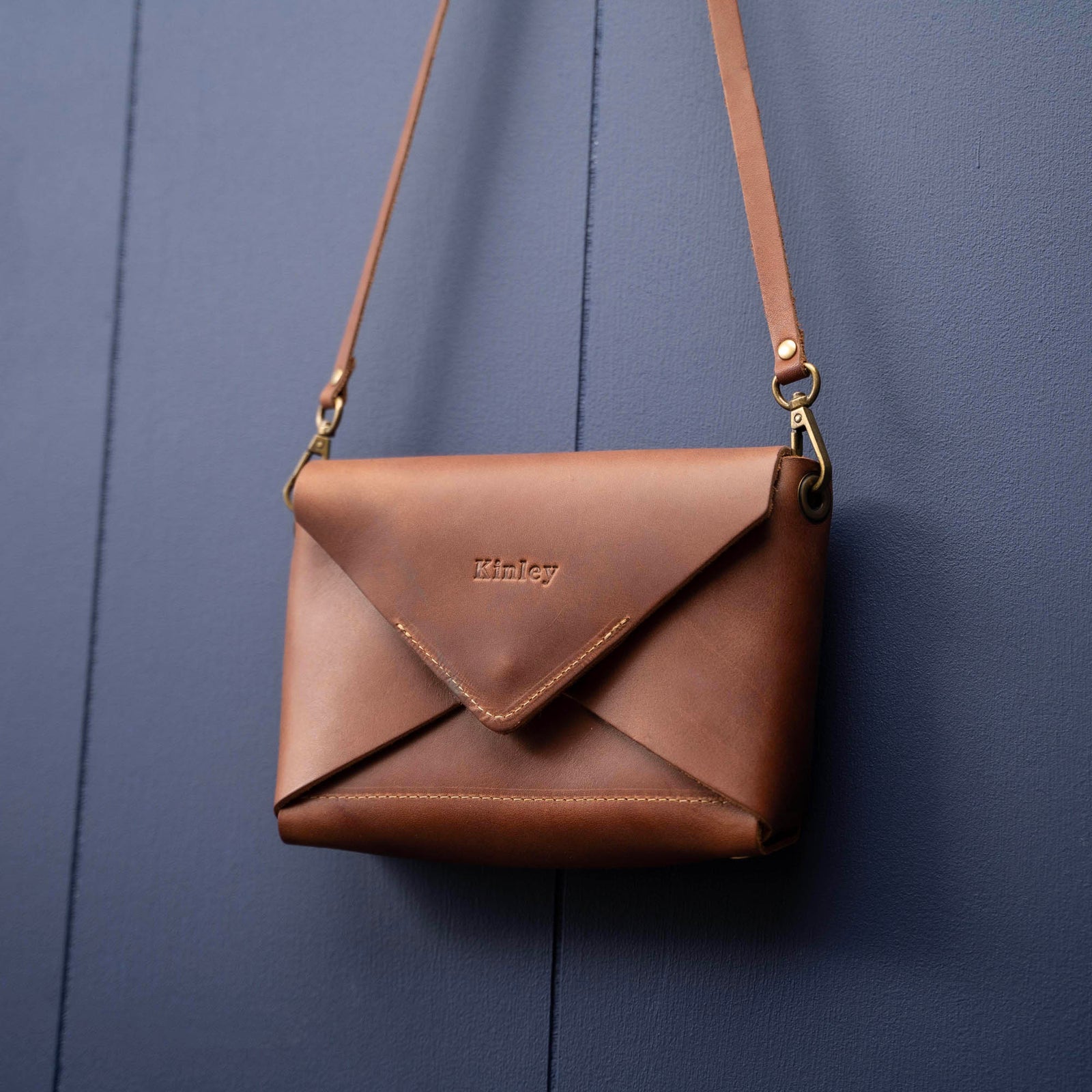 Handmade envelope purse featuring 3 in 1 leather strap. Wear as a clutch, wristlet, crossbody, or over the shoulder. Made with full grain leather. Available in black, brown, or tan.