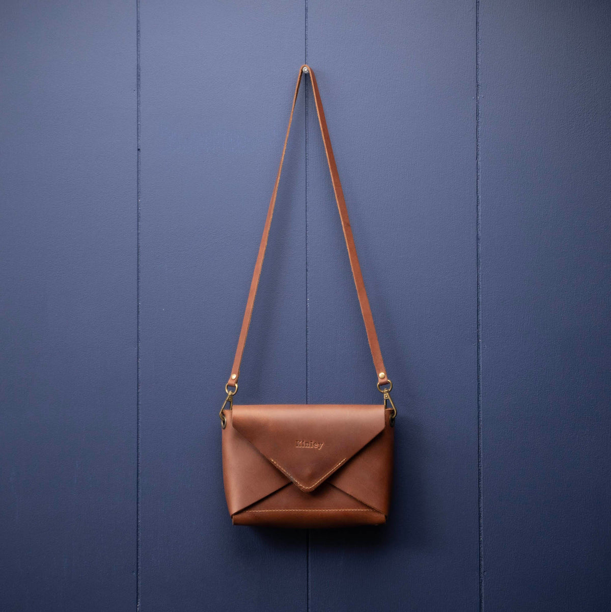 Handmade envelope purse featuring 3 in 1 leather strap. Wear as a clutch, wristlet, crossbody, or over the shoulder. Made with full grain leather. Available in black, brown, or tan.