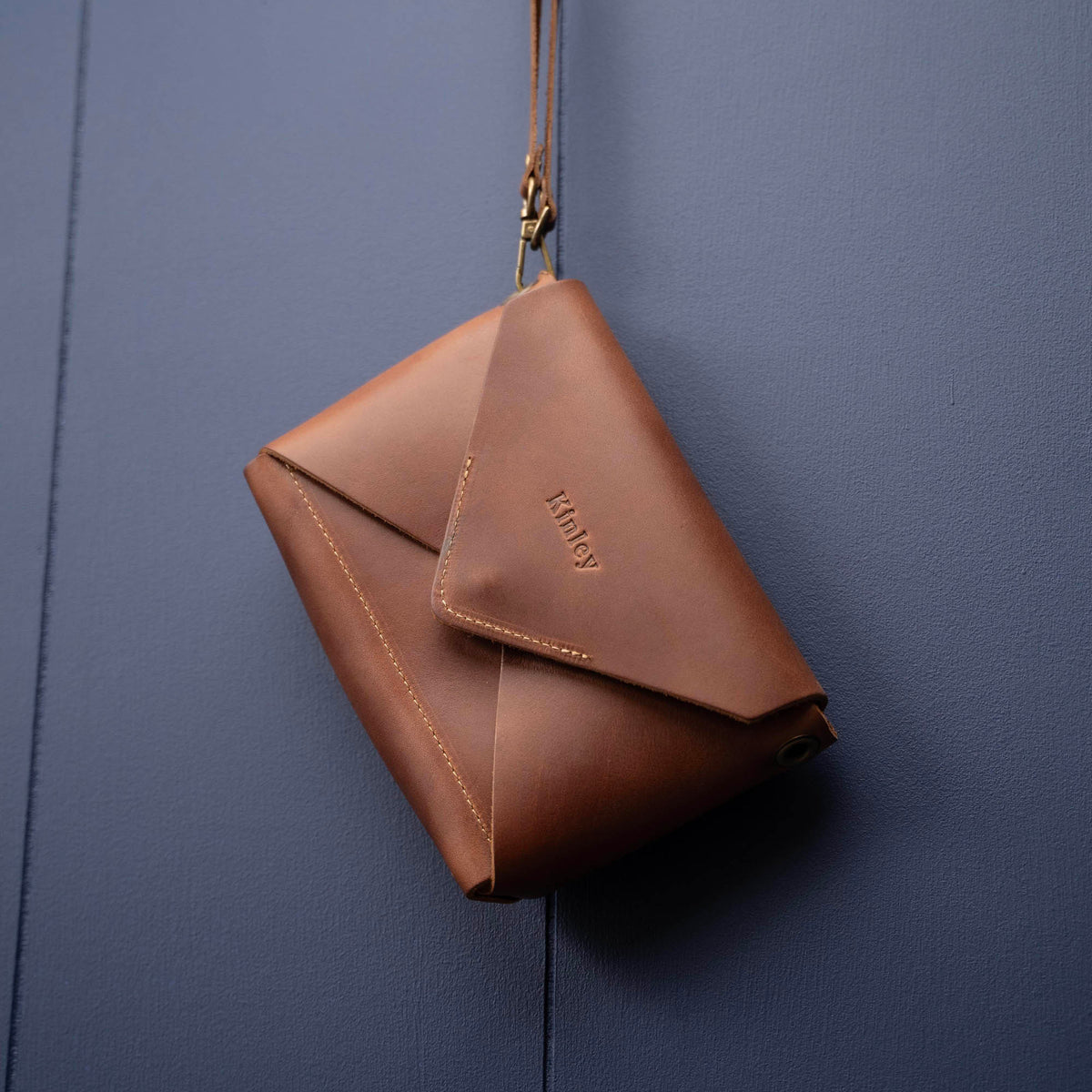Handmade envelope purse featuring 3 in 1 leather strap. Wear as a clutch, wristlet, crossbody, or over the shoulder. Made with full grain leather. Available in black, brown, or tan.