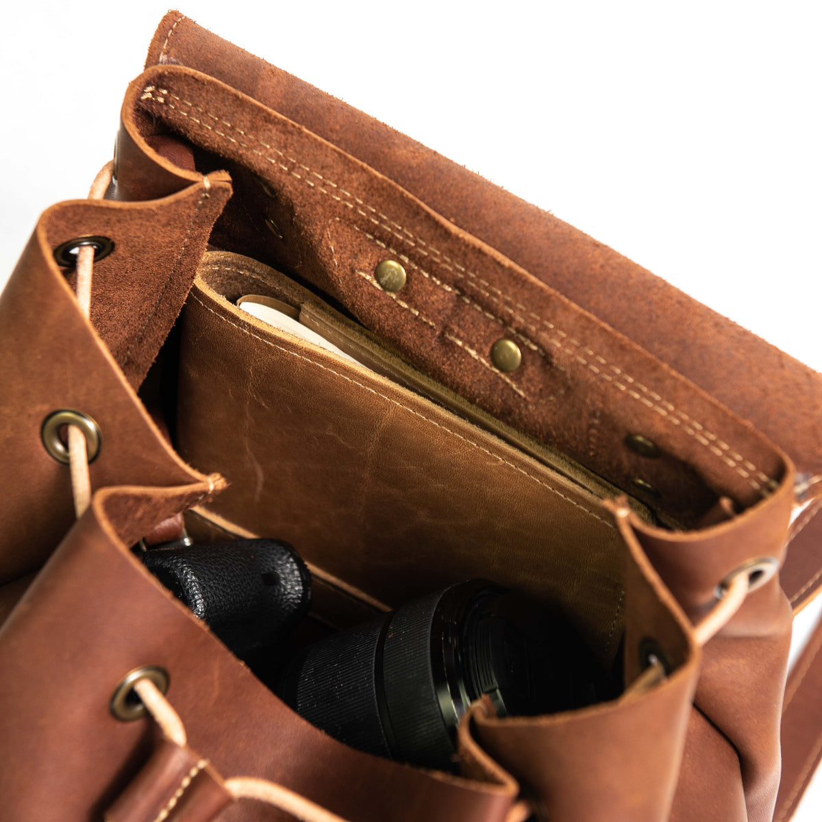 Hand made full grain leather backpack with drawstring slap closure. It features a main compartment with an interior pocket, two outer pockets, and a side pocket. Available in black or brown leather.